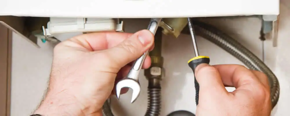 Boiler repair technician tightening pipe fittings and connections in Overland Park, KS