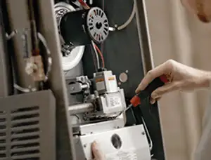 Furnace repair technician inspecting internal components and wiring in Overland Park, KS