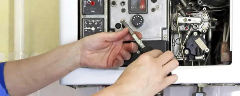 Heating repair technician adjusting boiler controls and components in Overland Park, KS