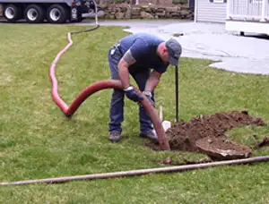 Septic pumping technician servicing a residential septic tank with a vacuum hose in Overland Park, KS
