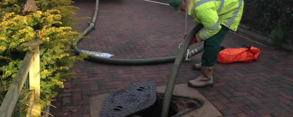 Septic tank cleaning technician servicing a septic tank with a vacuum hose in Overland Park, KS