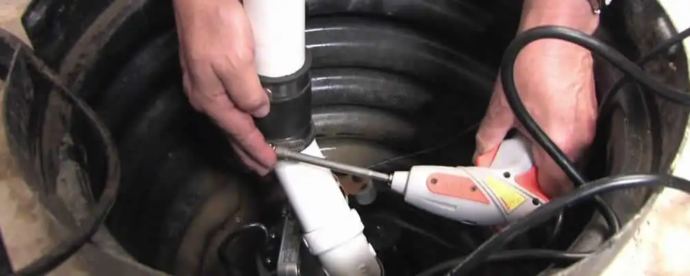 Sump pump installation technician connecting PVC discharge piping in Overland Park, KS