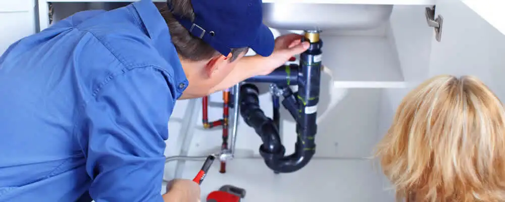 Plumber repairing under-sink drain pipes and fittings in Overland Park, KS